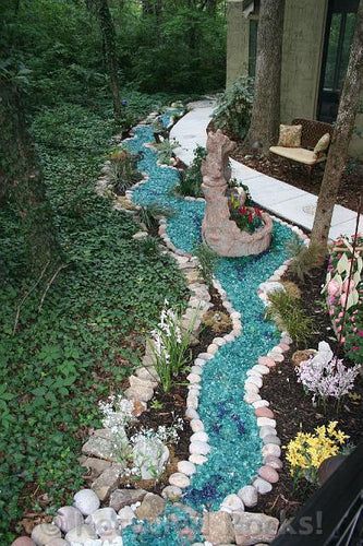 A garden with a stream made of glass rocks and flowers.