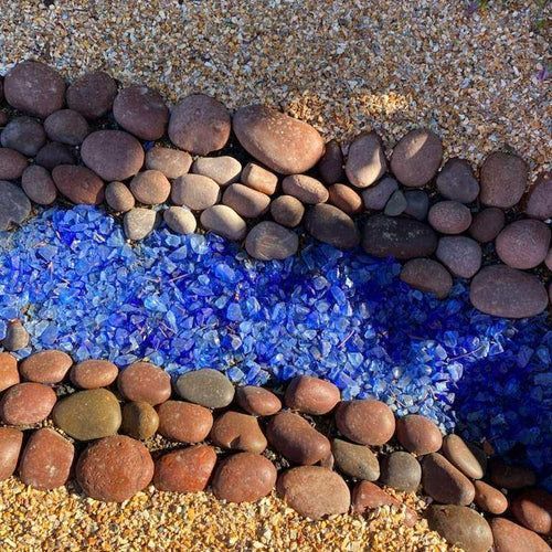 A pile of rocks and blue glass on the ground.