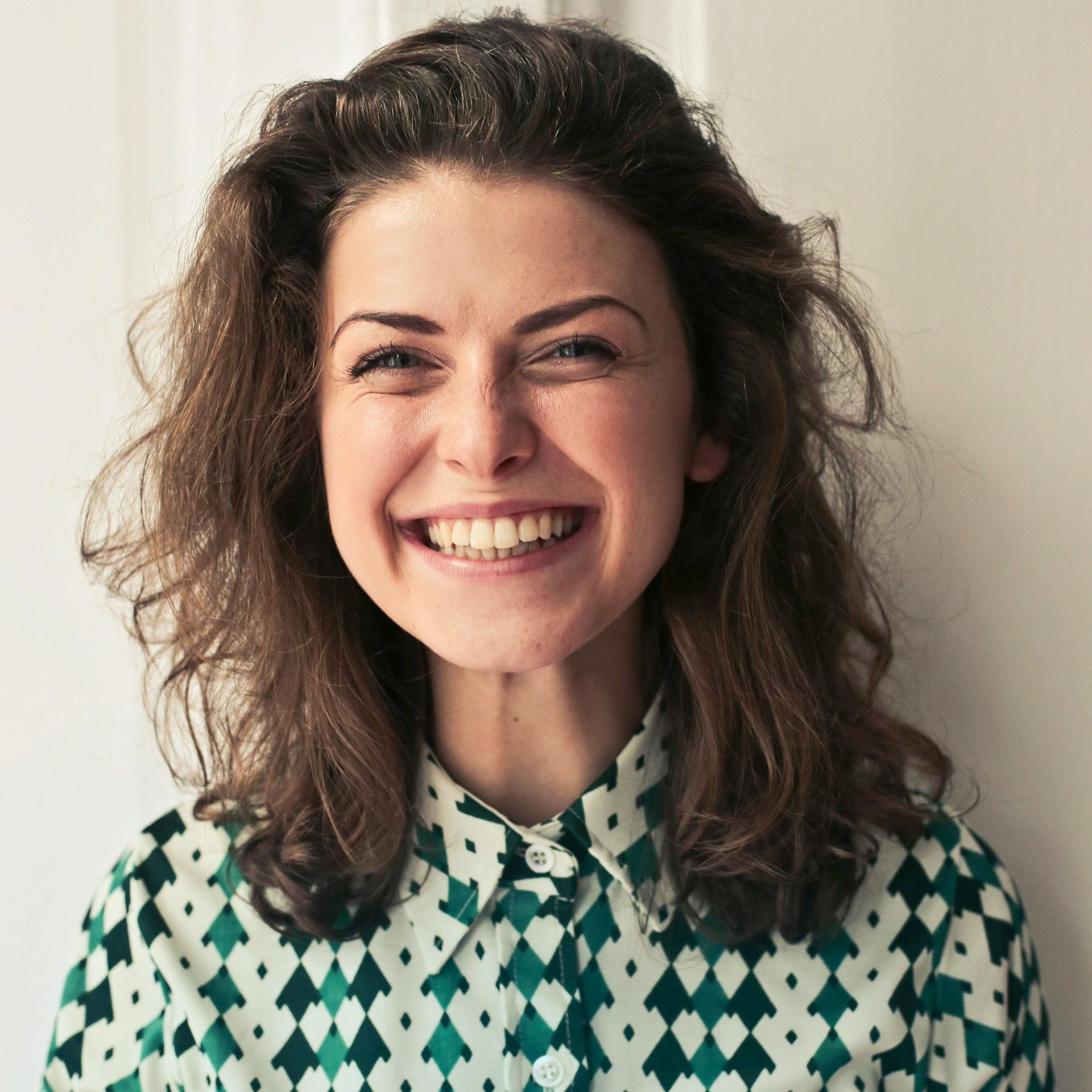 A woman wearing a green and white checkered shirt is smiling.
