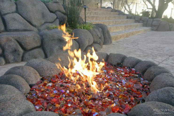 A fire pit surrounded by rocks with a staircase in the background