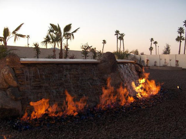 A waterfall with flames coming out of it and palm trees in the background
