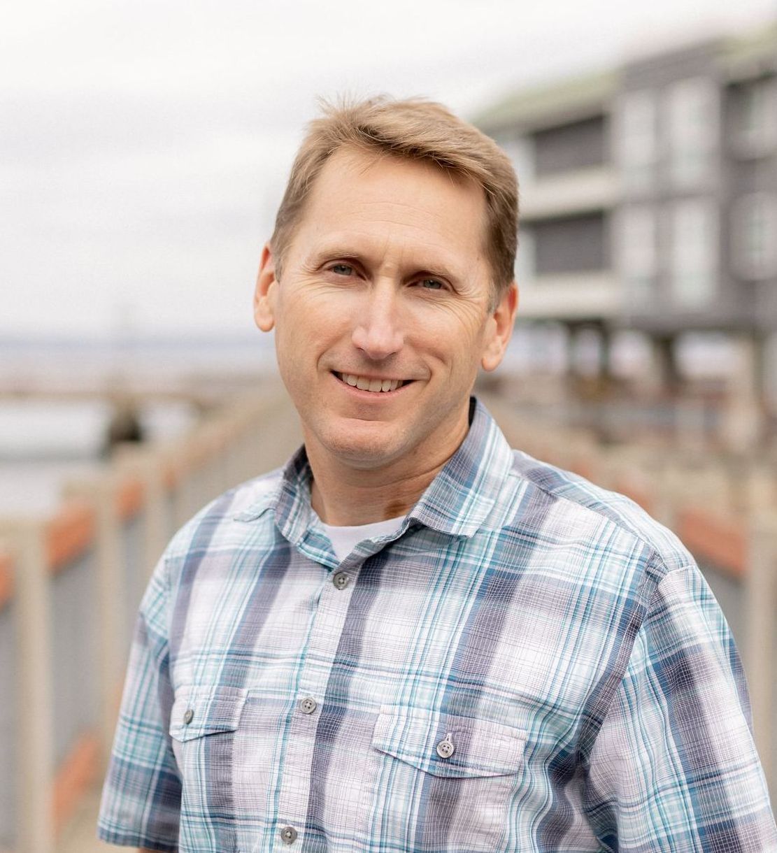 A man in a plaid shirt is smiling for the camera.