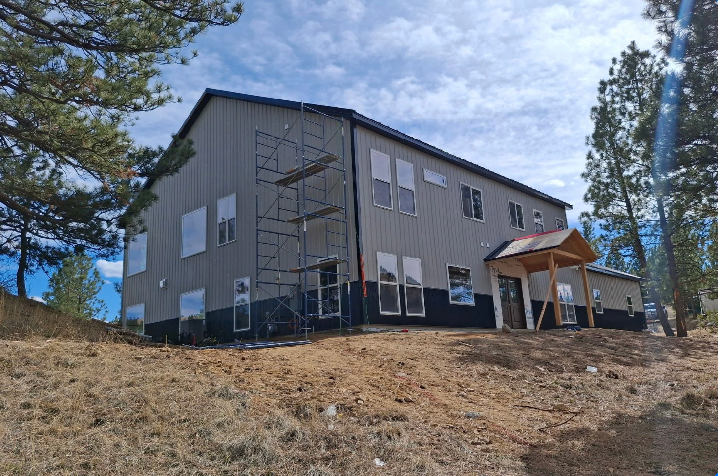 A white, single-story home with a central entrance, two dormer windows, a brick chimney, and black shutters on a lawn.