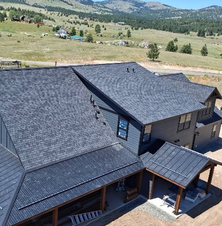 Two newly constructed beige suburban houses with white garage doors under a blue sky with scattered clouds.