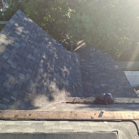 A two-story tan and white house under construction, with wooden ladders leaning against the exterior and roof.