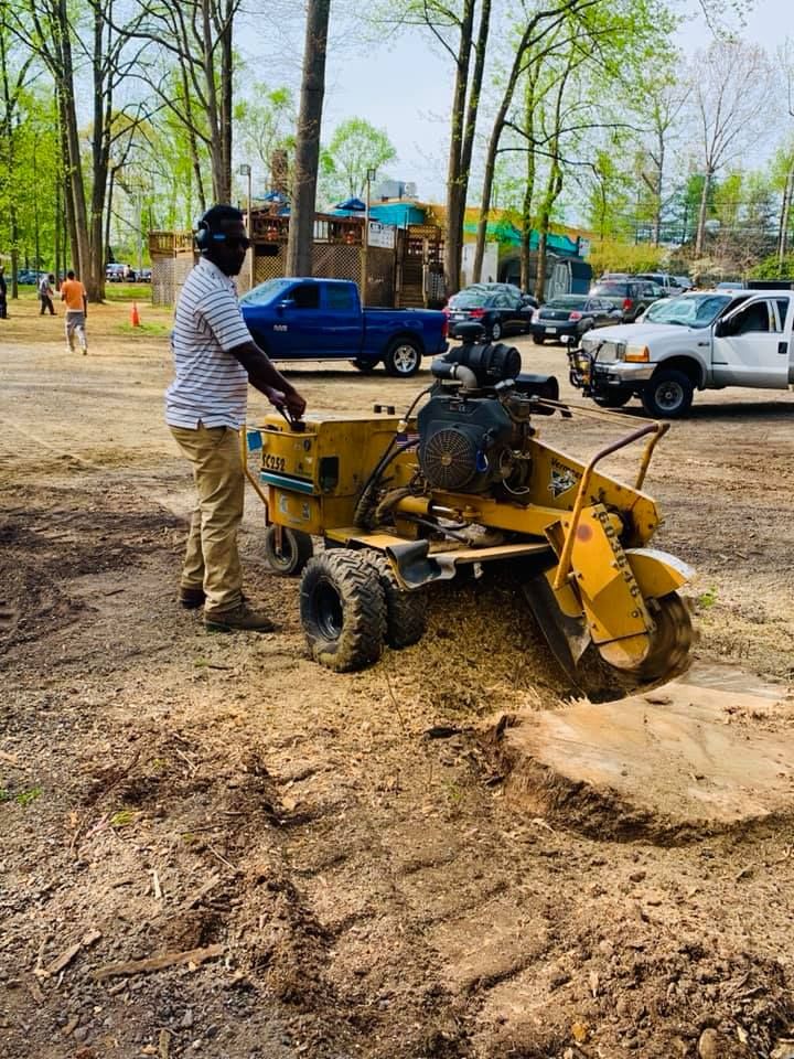 a man is standing next to a stump grinder in a parking lot .