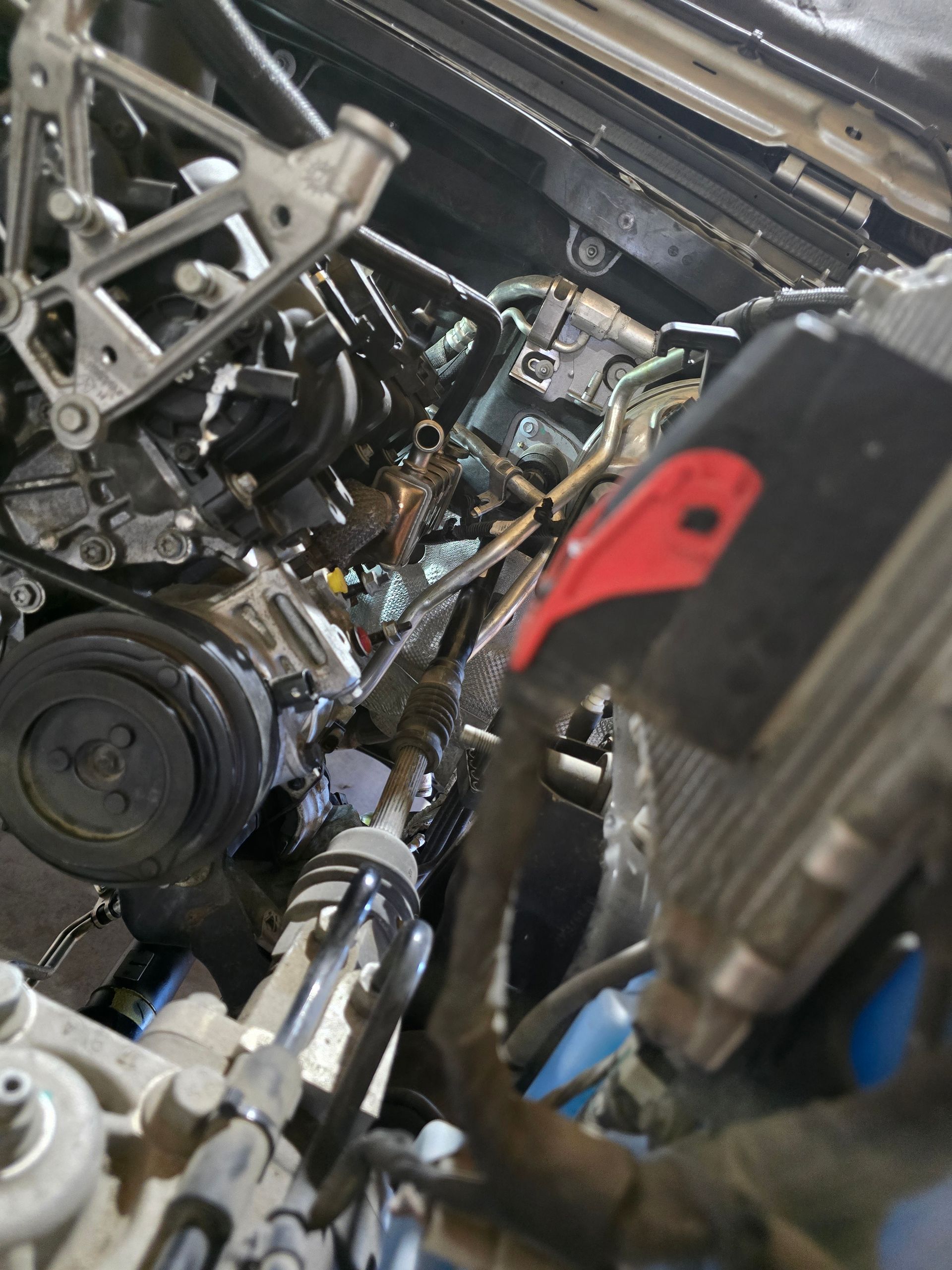 Person cleaning a car engine with a spray bottle, outdoors.