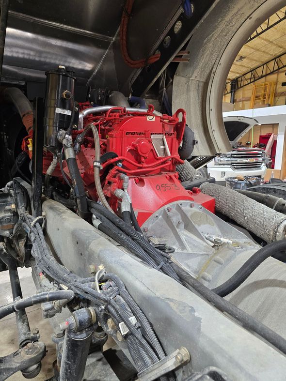 Mechanic's hand working on a car's transmission undercarriage, visible oil and parts.