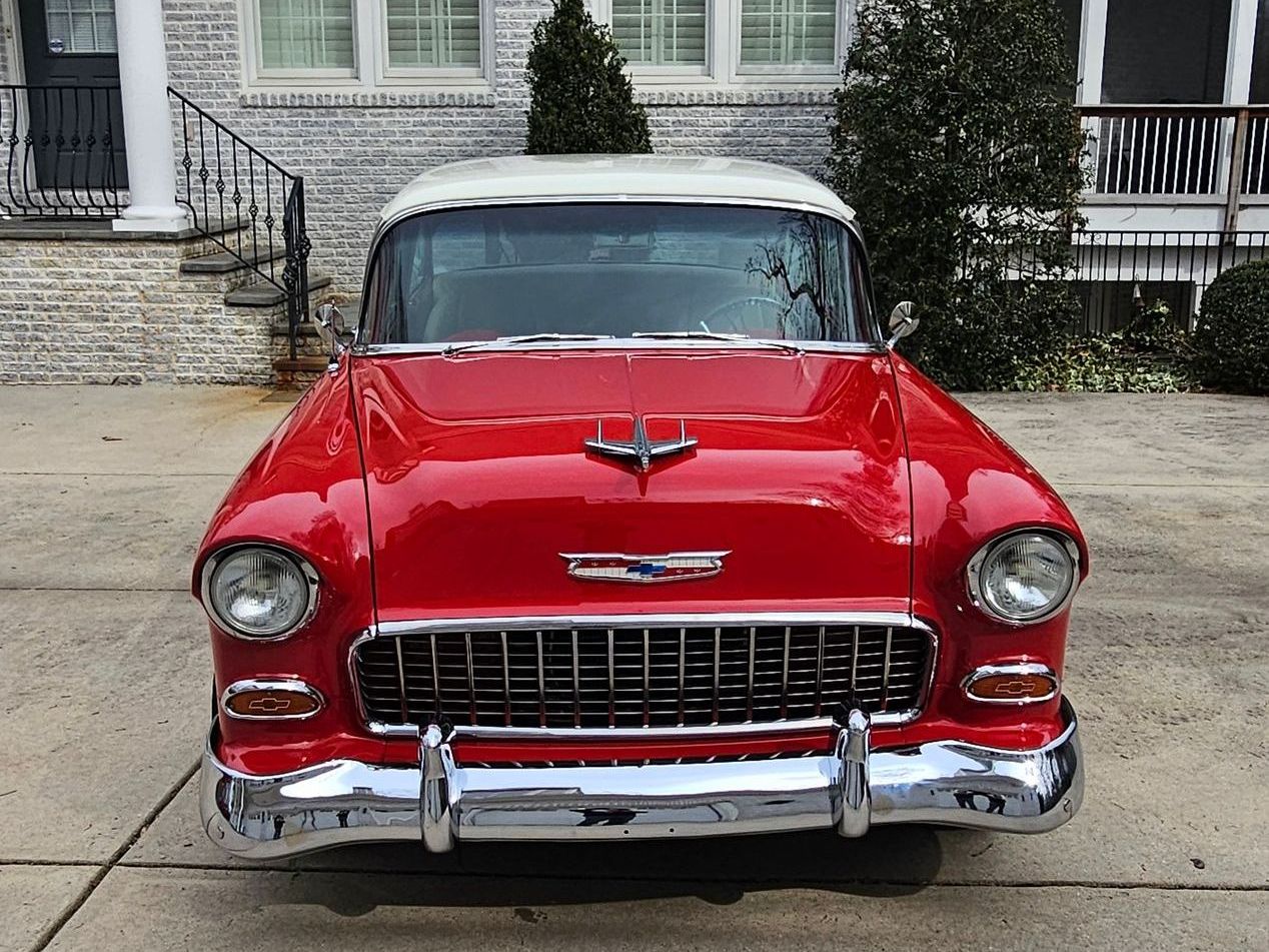 Red and white classic Chevrolet Bel Air parked in front of a house.