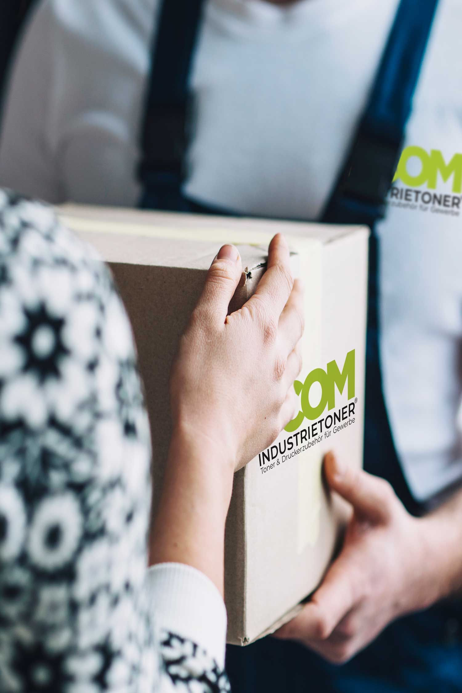 Person, die von einem Lieferanten einen Karton entgegennimmt.