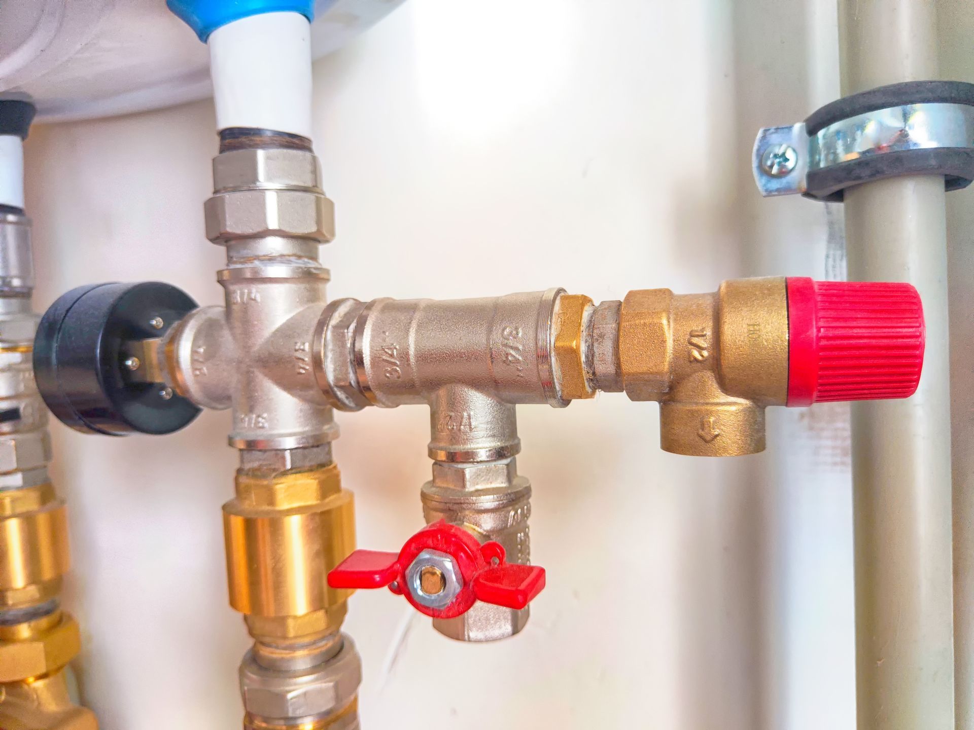 A close up of a valve on a pipe with a red cap.