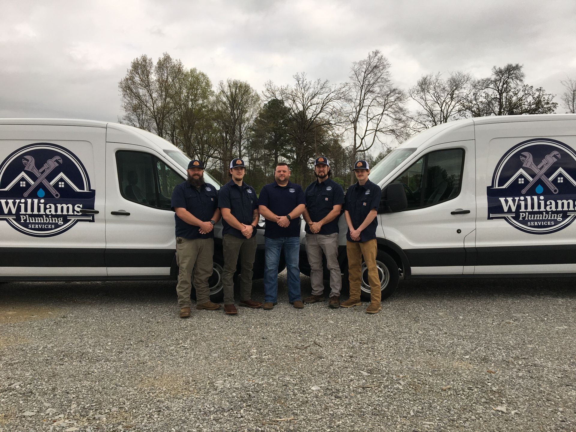 A group of men standing in front of two williams vans.
