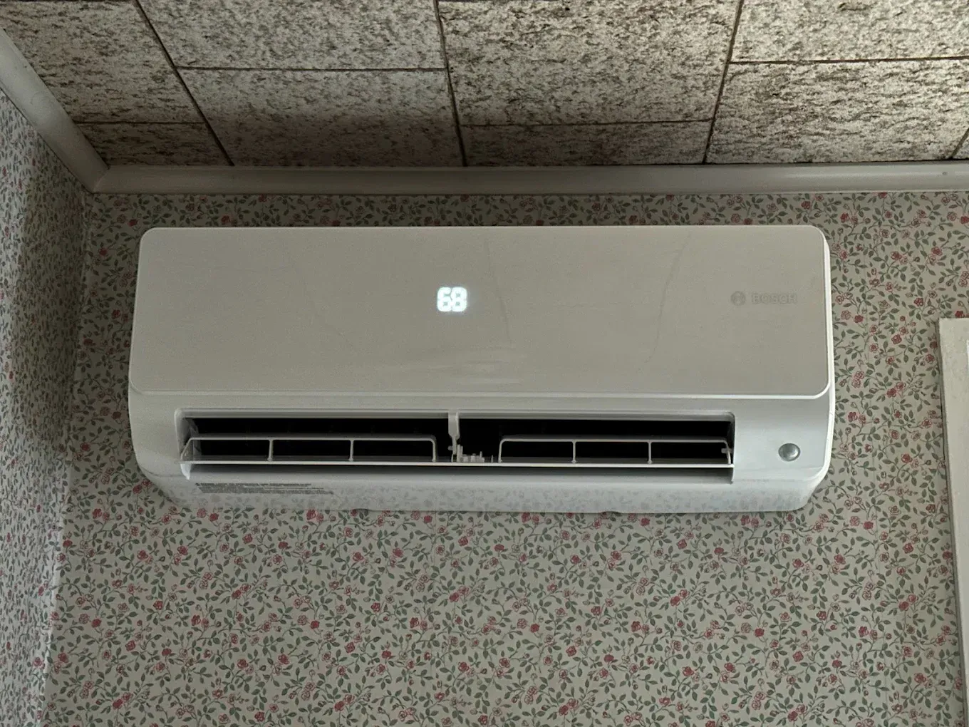 A white air conditioner is hanging on a wall in a room.