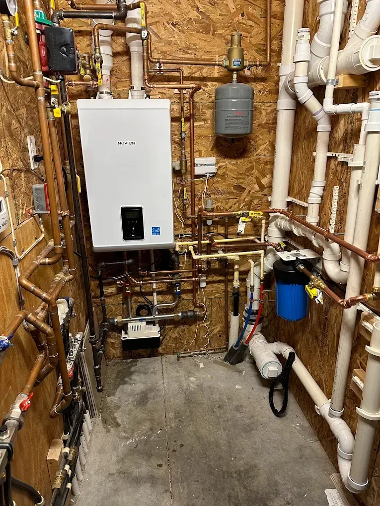 A room filled with lots of pipes and a boiler.