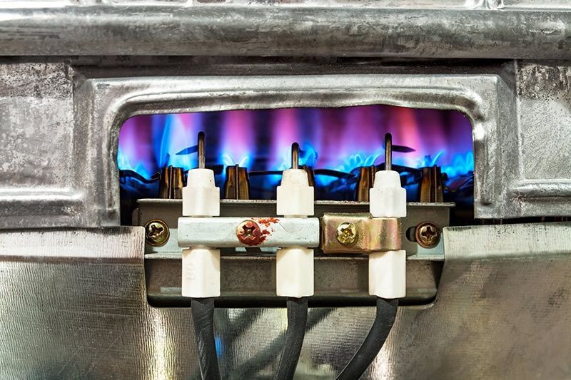 A close up of a gas burner with flames coming out of it.