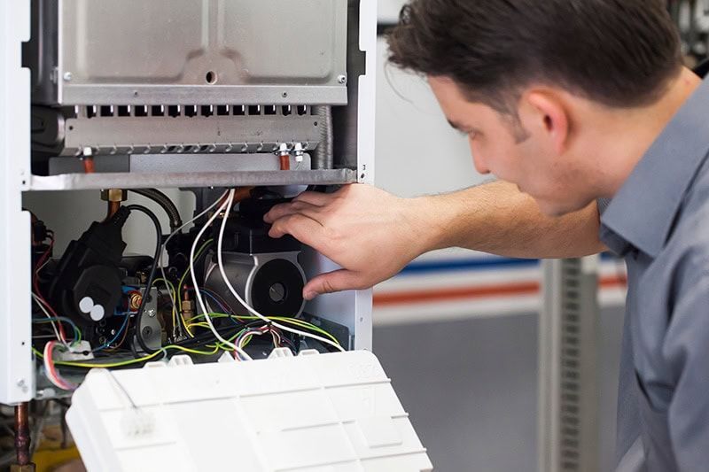 A man is working on a boiler in a factory.