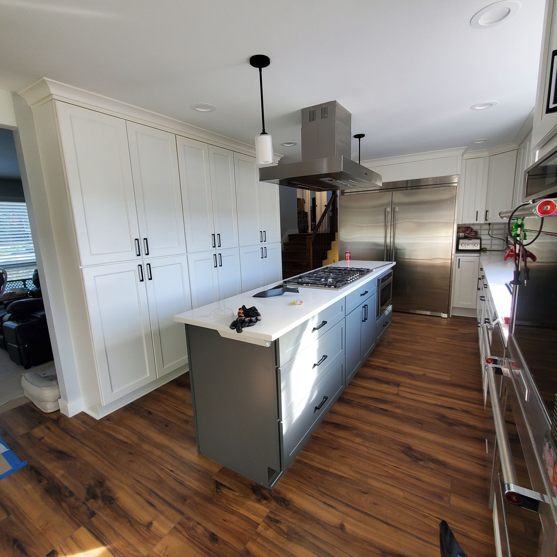 Modern kitchen with a large island, stainless steel appliances, and light wood floors.