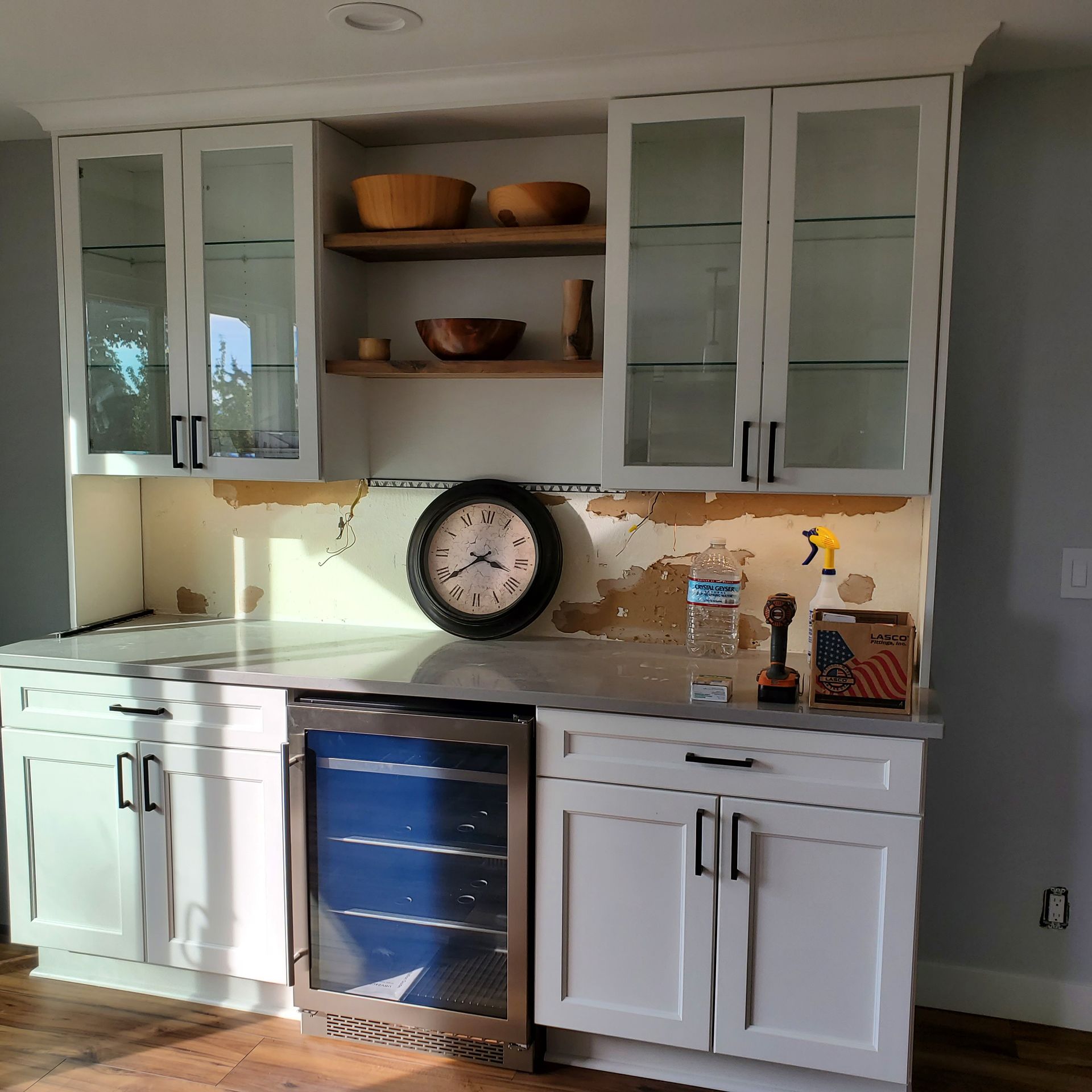White cabinets with wine cooler, wood shelves, and clock on a countertop.