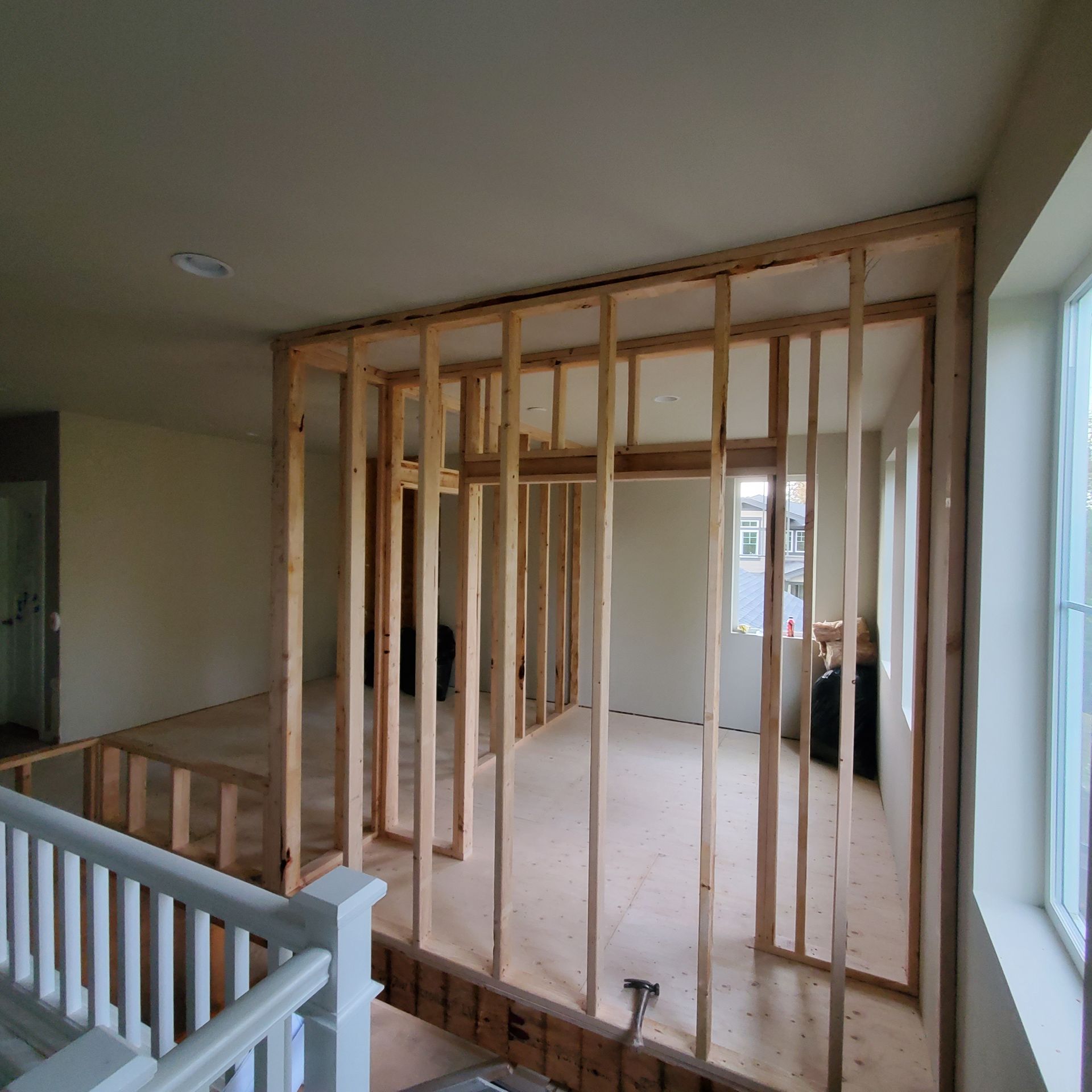 Interior view of a room under construction; wooden frame studs outline the walls, the floor, and the ceiling.