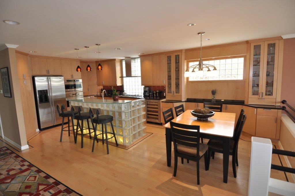 Modern kitchen with island, stainless steel appliances, wood flooring, and large window.