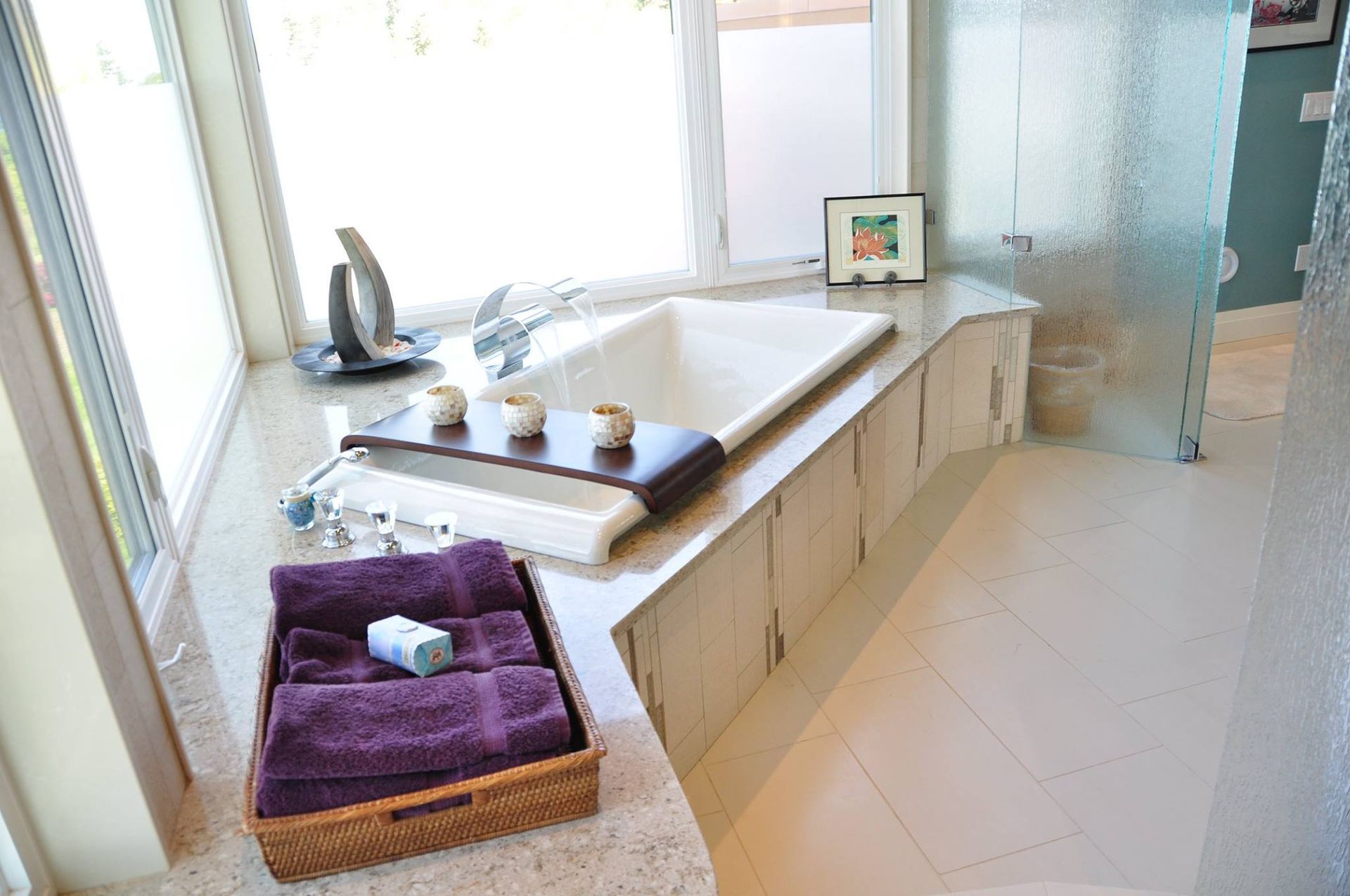 Bathroom with a white tub, purple towels, and a window.