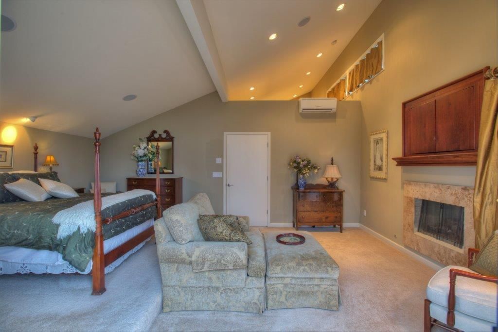 Spacious bedroom with bed, sitting area, fireplace, neutral colors.