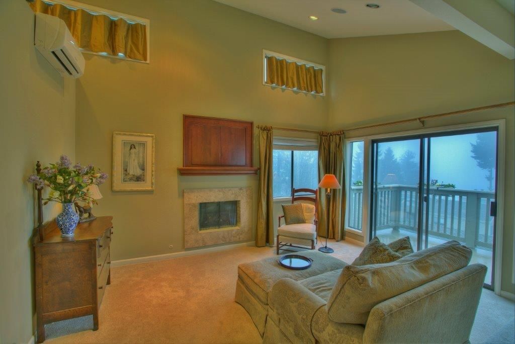 Cozy living room with fireplace, sofa, and balcony overlooking a foggy outdoor view.