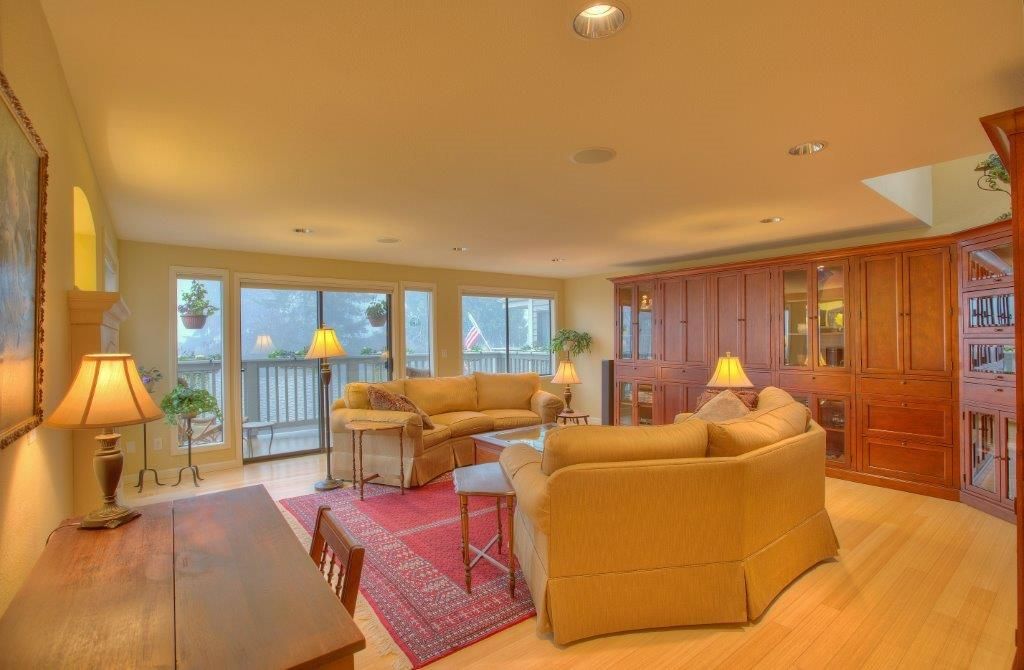 Living room with beige sofas, wooden cabinetry, and sliding glass doors to a deck.