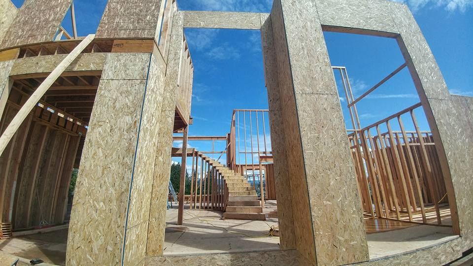 Construction site with wooden frame, clear blue sky visible through openings.
