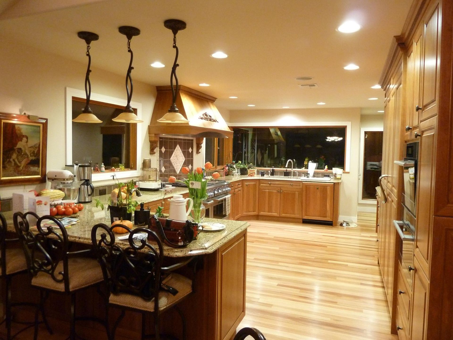 A well-lit kitchen with a large island, wooden cabinets, and a cooktop; warm colors.