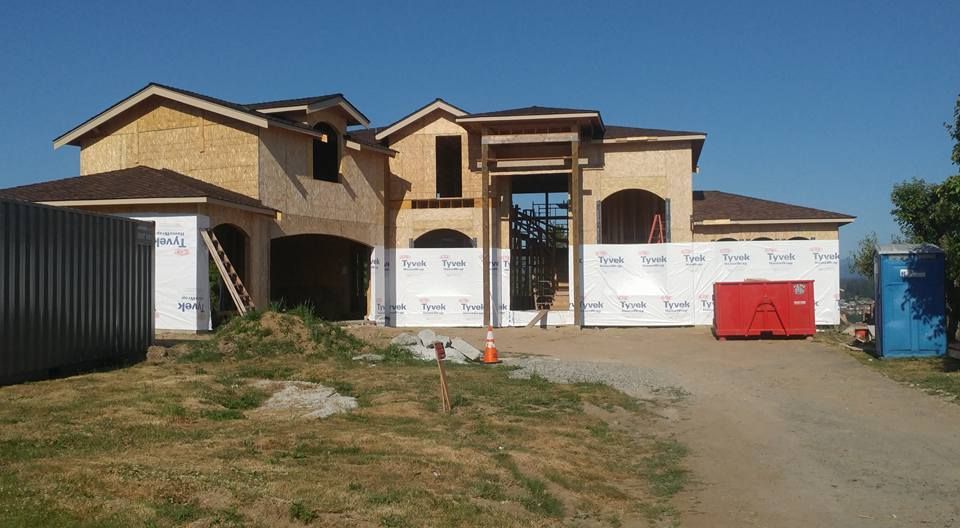 House under construction, wood frame, cloudy sky.