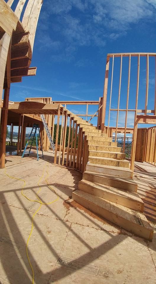 Wooden spiral staircase under construction against a blue sky.