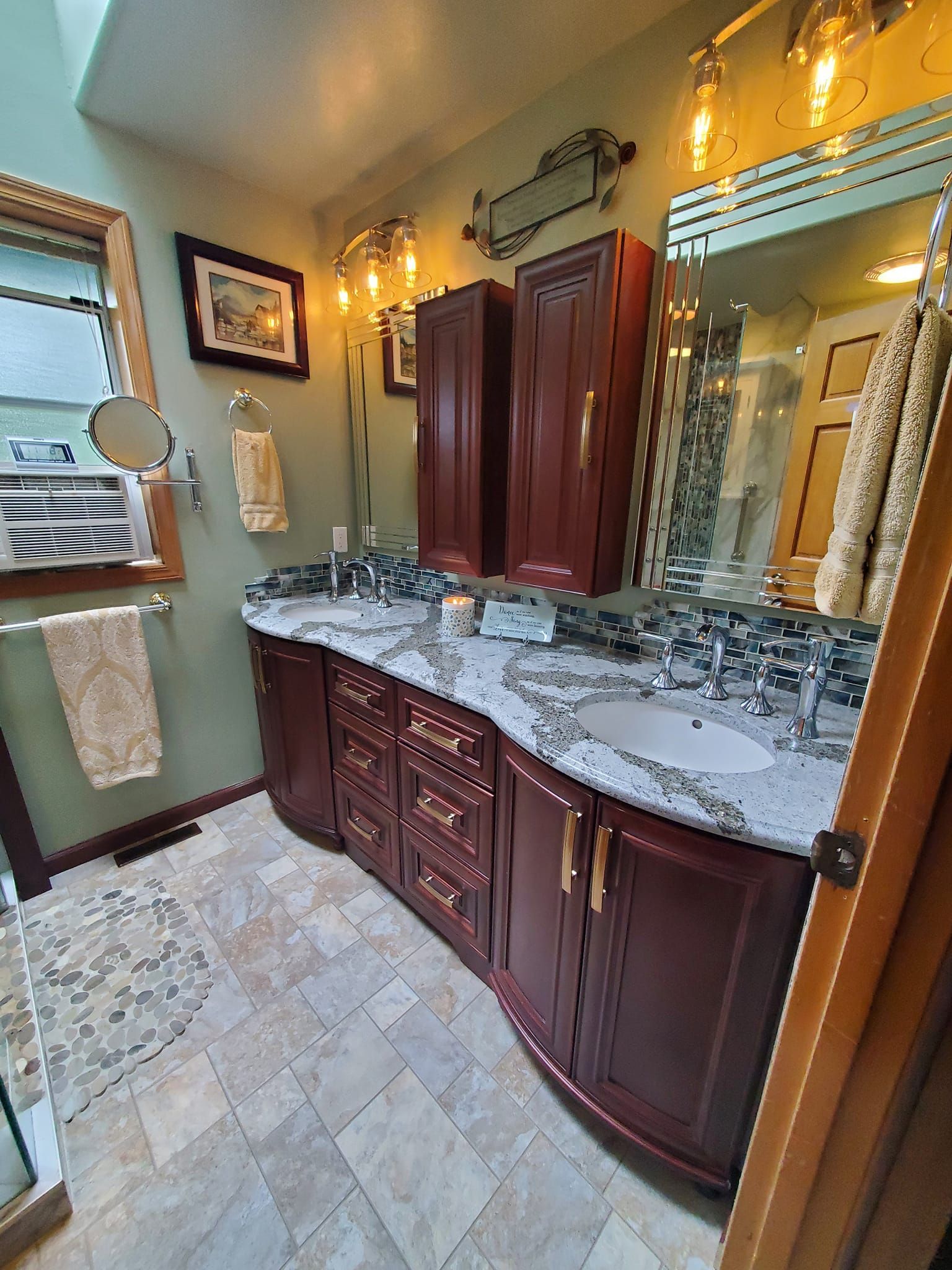 Bathroom with a curved, cherry-wood vanity, marble countertop, and two sinks.