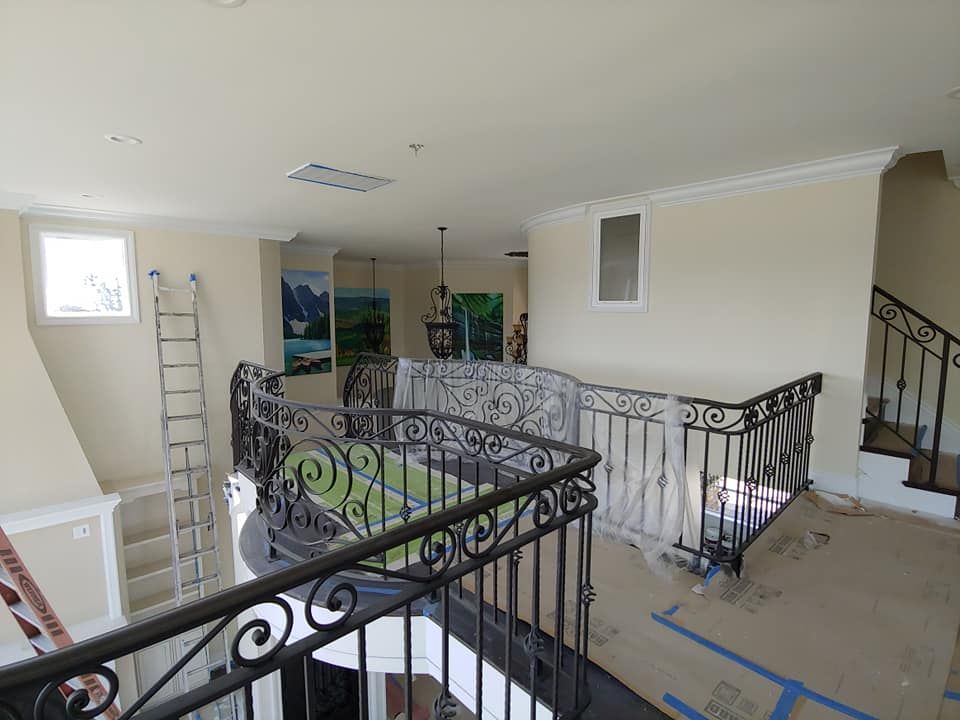 Interior view of a second-story hallway with ornate black railing and a staircase.