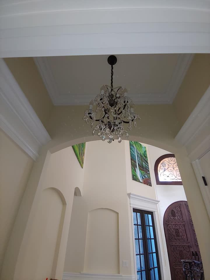 Elegant foyer with crystal chandelier, arched doorways, and colorful artwork.