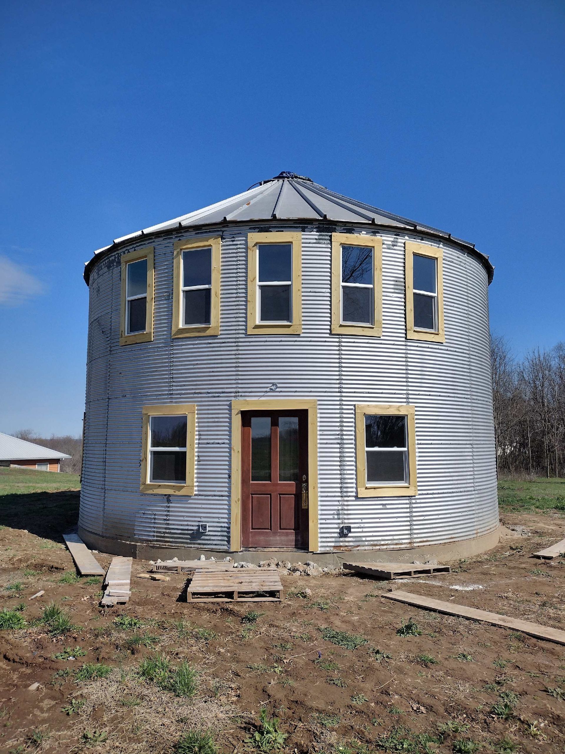 A round building with a red door and windows in a field.