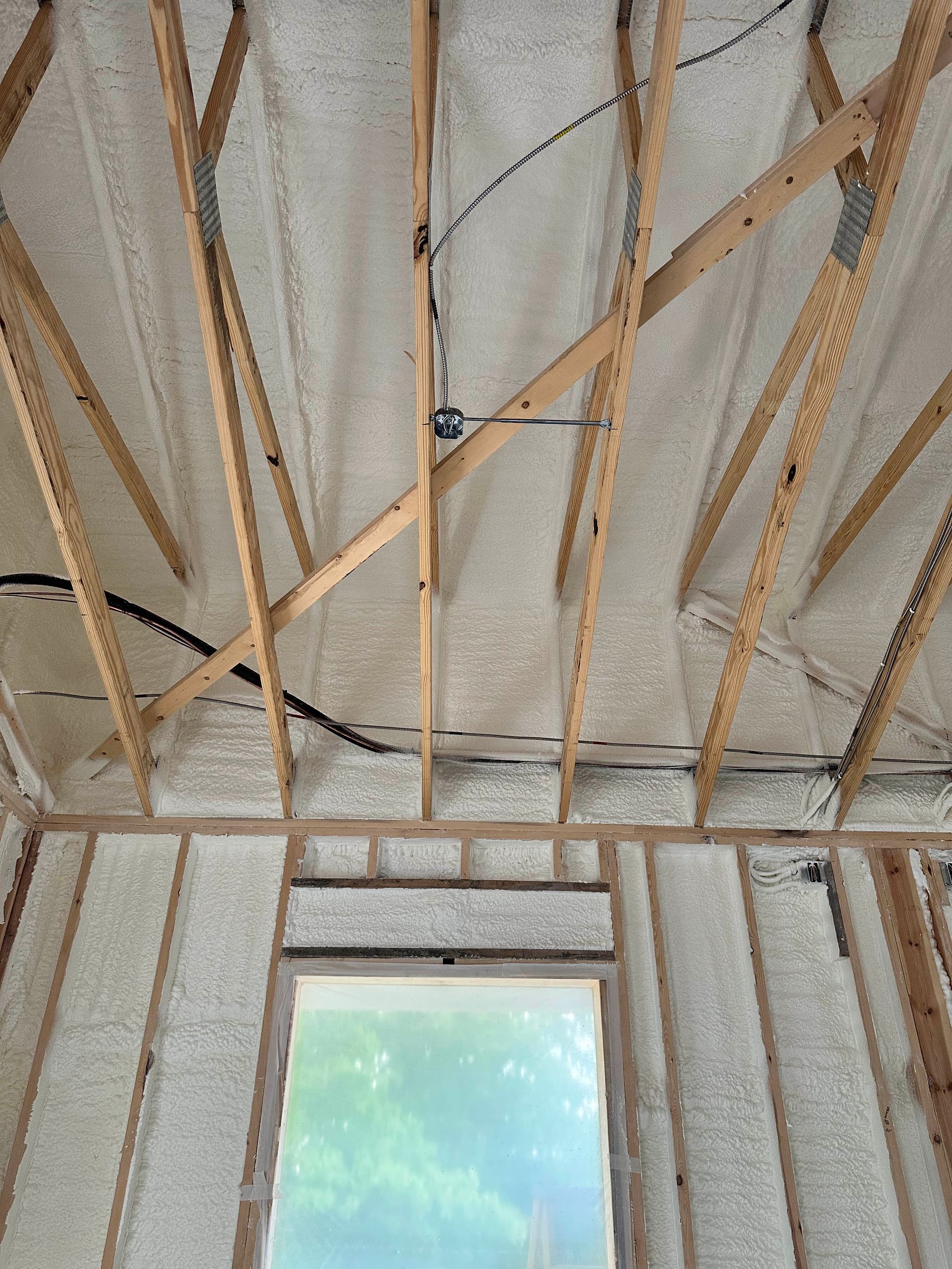 A room with a window and a ceiling covered in spray foam.