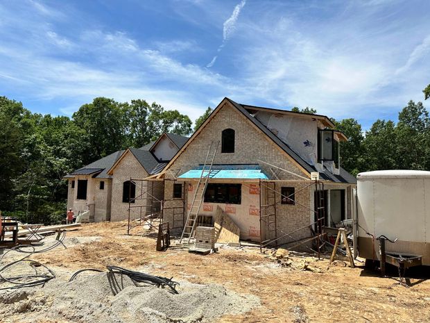 A large house is being built in the middle of a dirt field.
