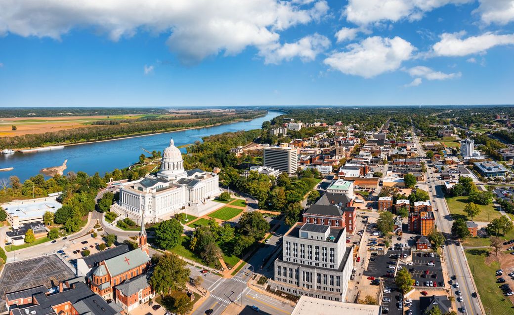 An aerial view of Jefferson City, Missouri with a river and a capitol building.