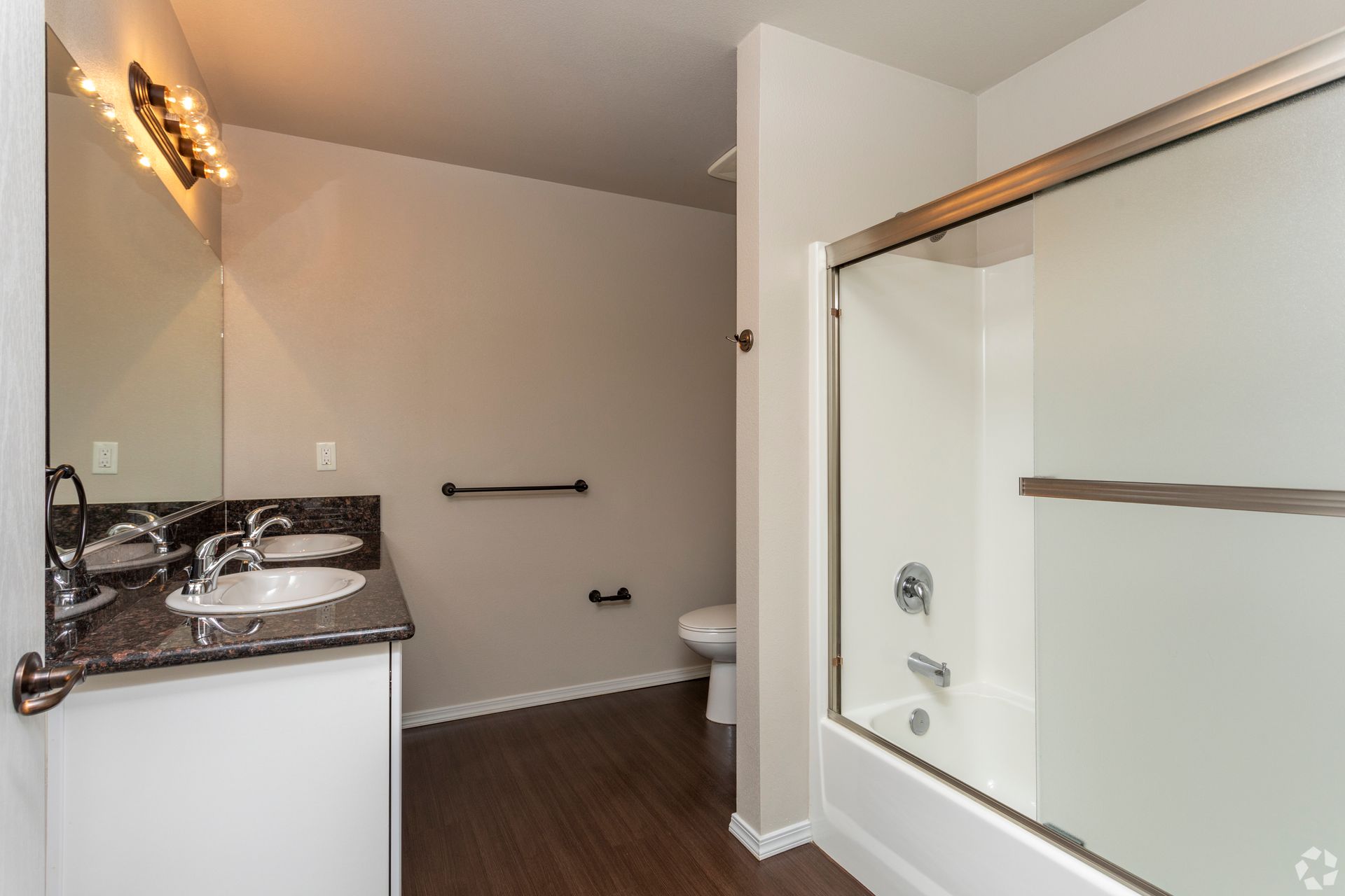 Bathroom with white fixtures, a dark countertop, and a dark wooden floor.