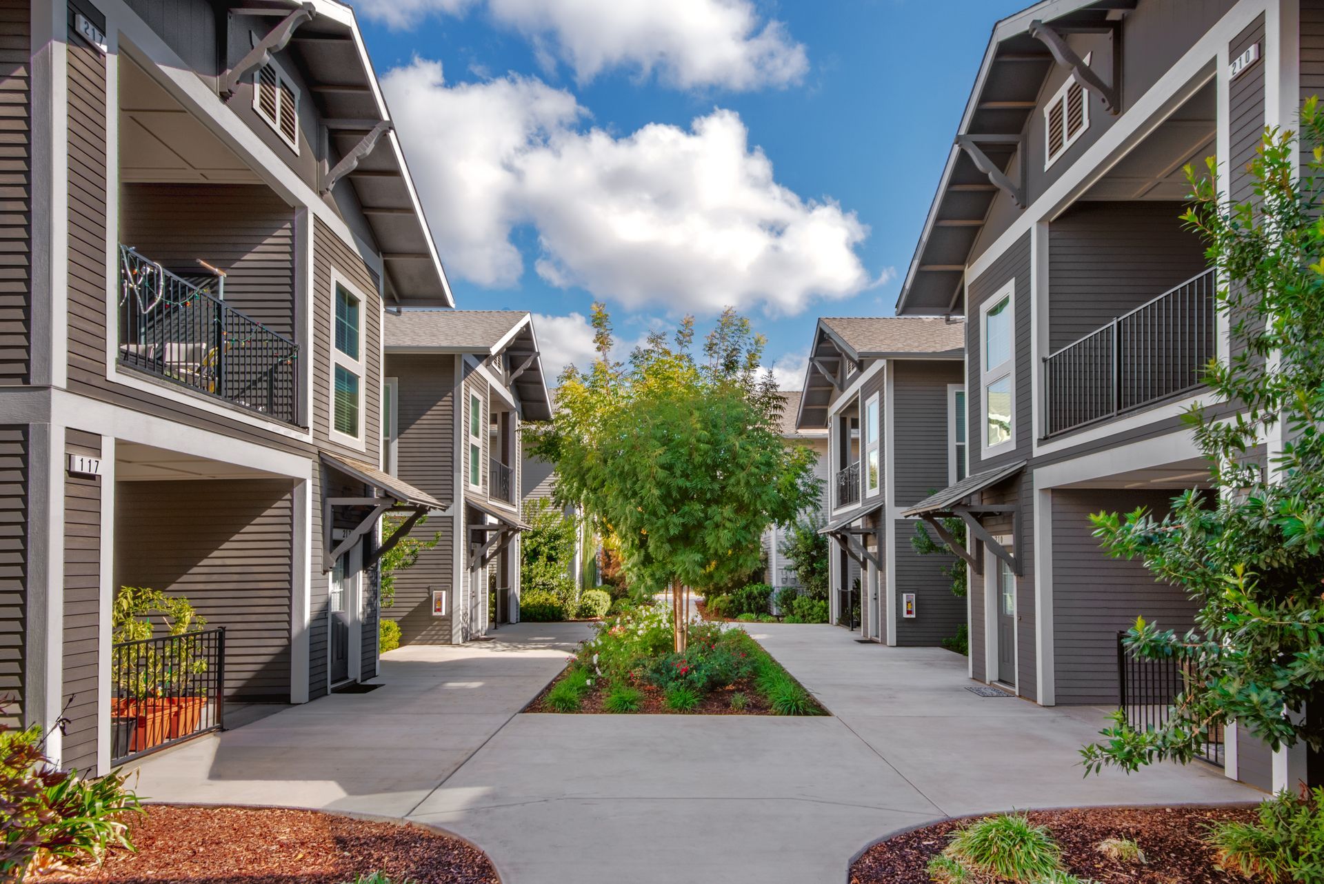 Townhouses with gray siding and white trim, facing each other around a landscaped courtyard.