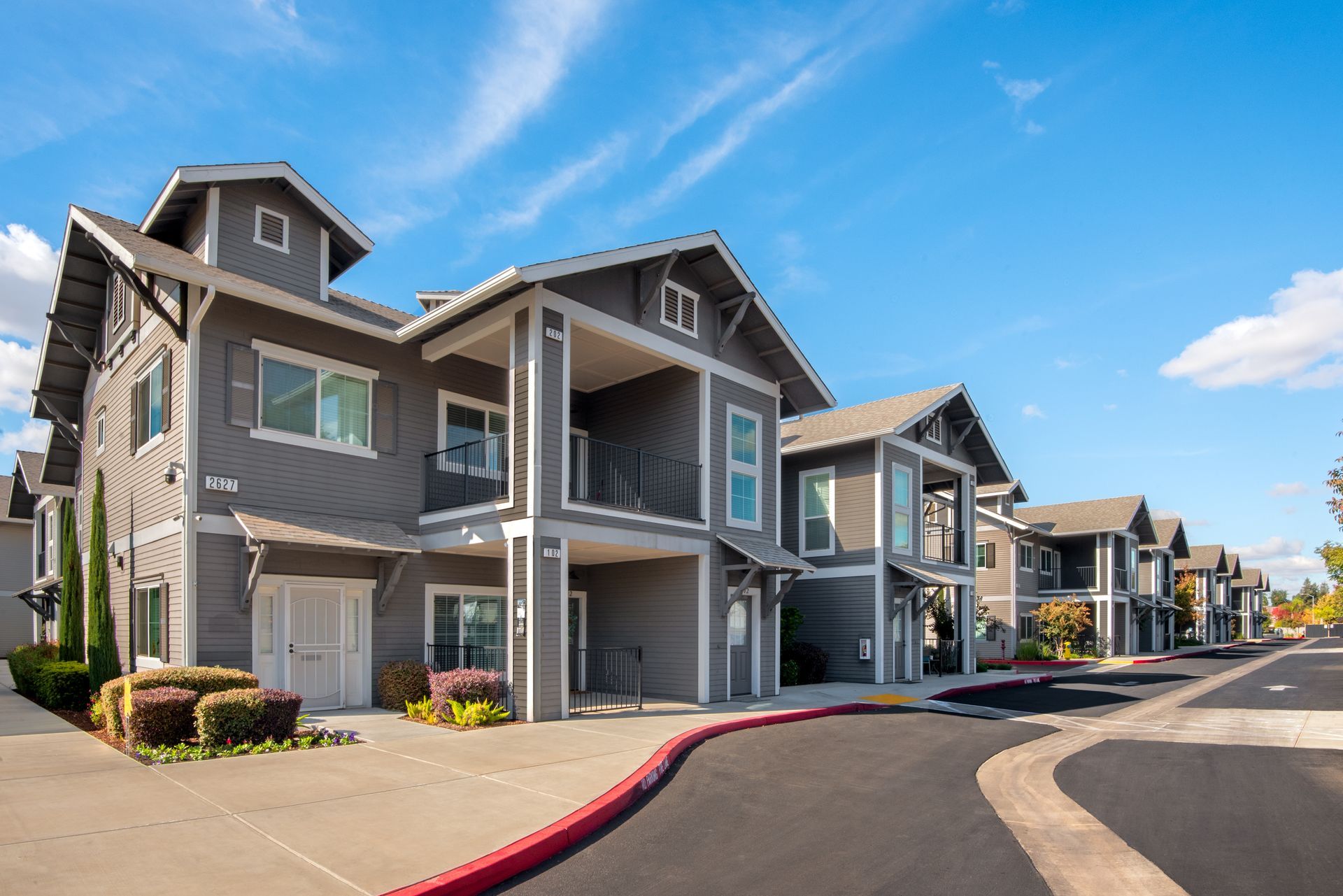 Gray apartment buildings with balconies under a blue sky.