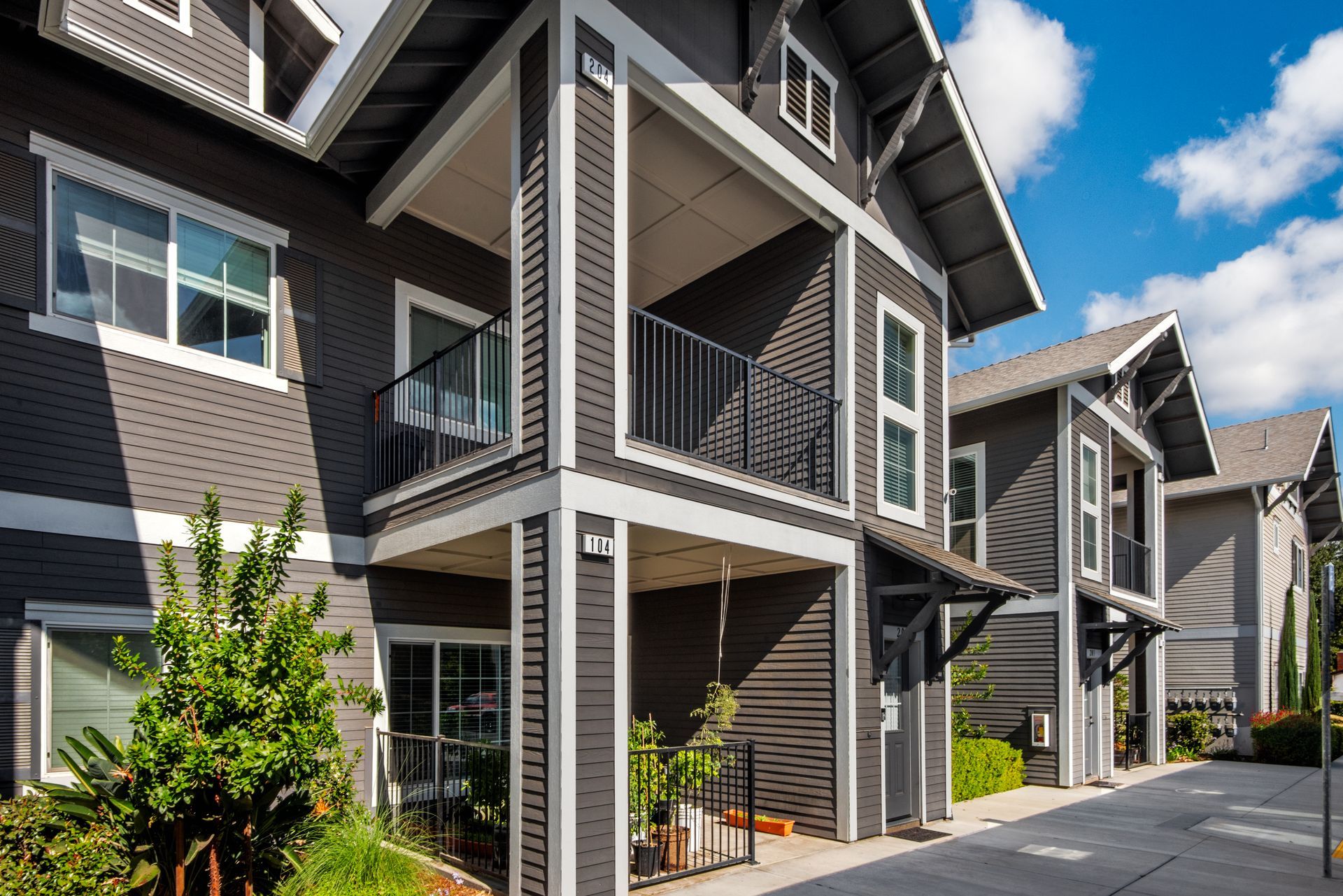 Gray apartment buildings with balconies under a blue sky.