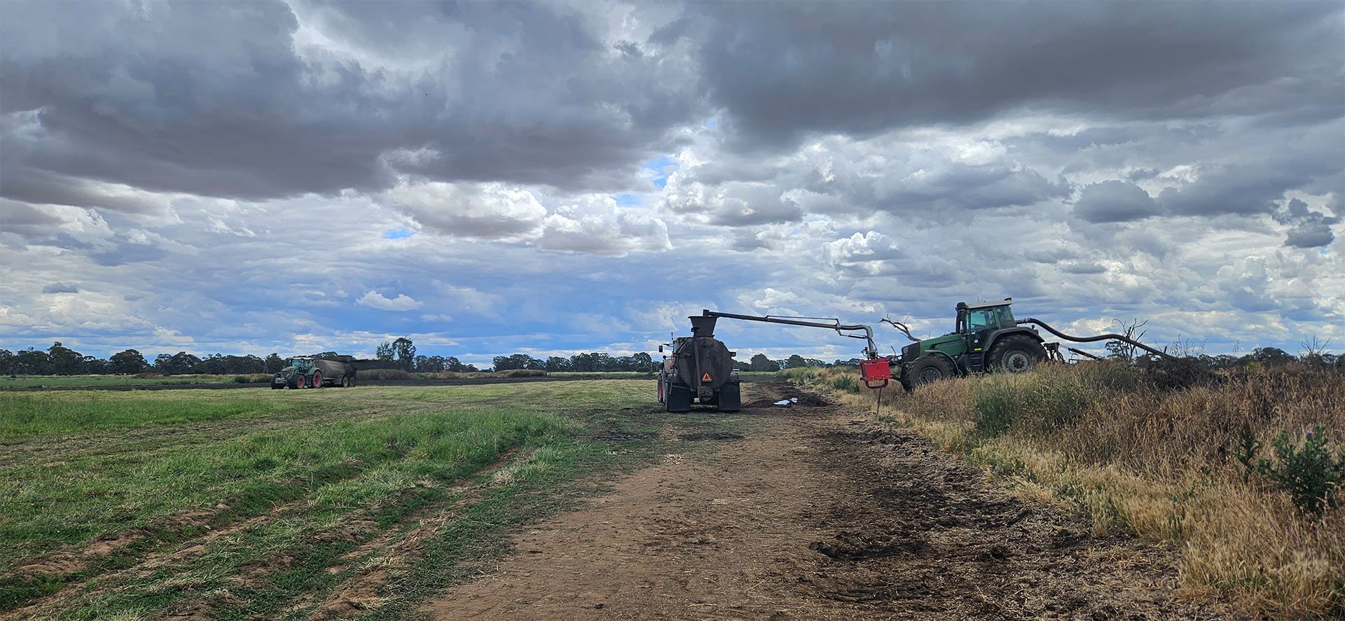 a tractor is plowing a field on a cloudy day .