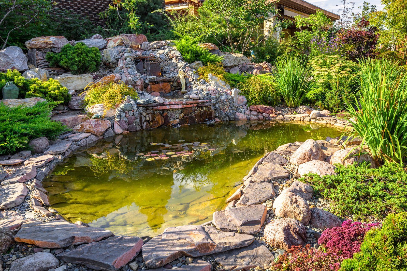 Close-up view of a meticulously designed home garden landscape featuring a charming small pond and a gentle waterfall.