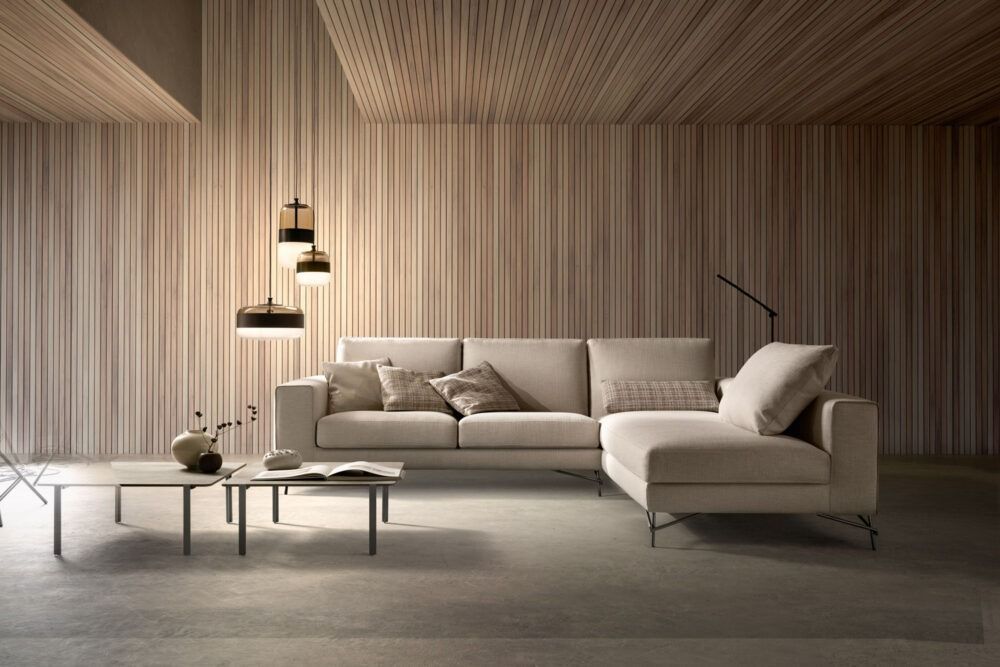Un soggiorno moderno con pareti beige, un divano componibile, un tavolino da caffè e lampade a sospensione.