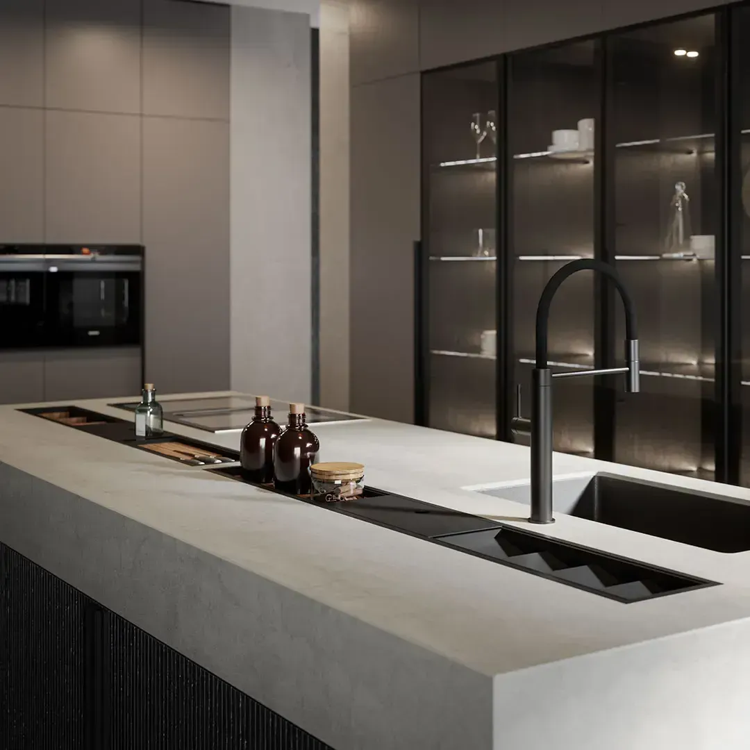 Cucina moderna con piano di lavoro grigio a isola, rubinetto nero e vetrine in vetro. Sono visibili anche pannelli in legno scuro ed elettrodomestici da incasso.