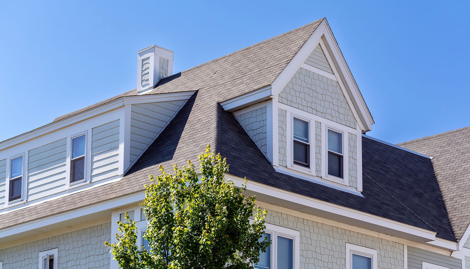 A house with a chimney on the roof and a tree in front of it