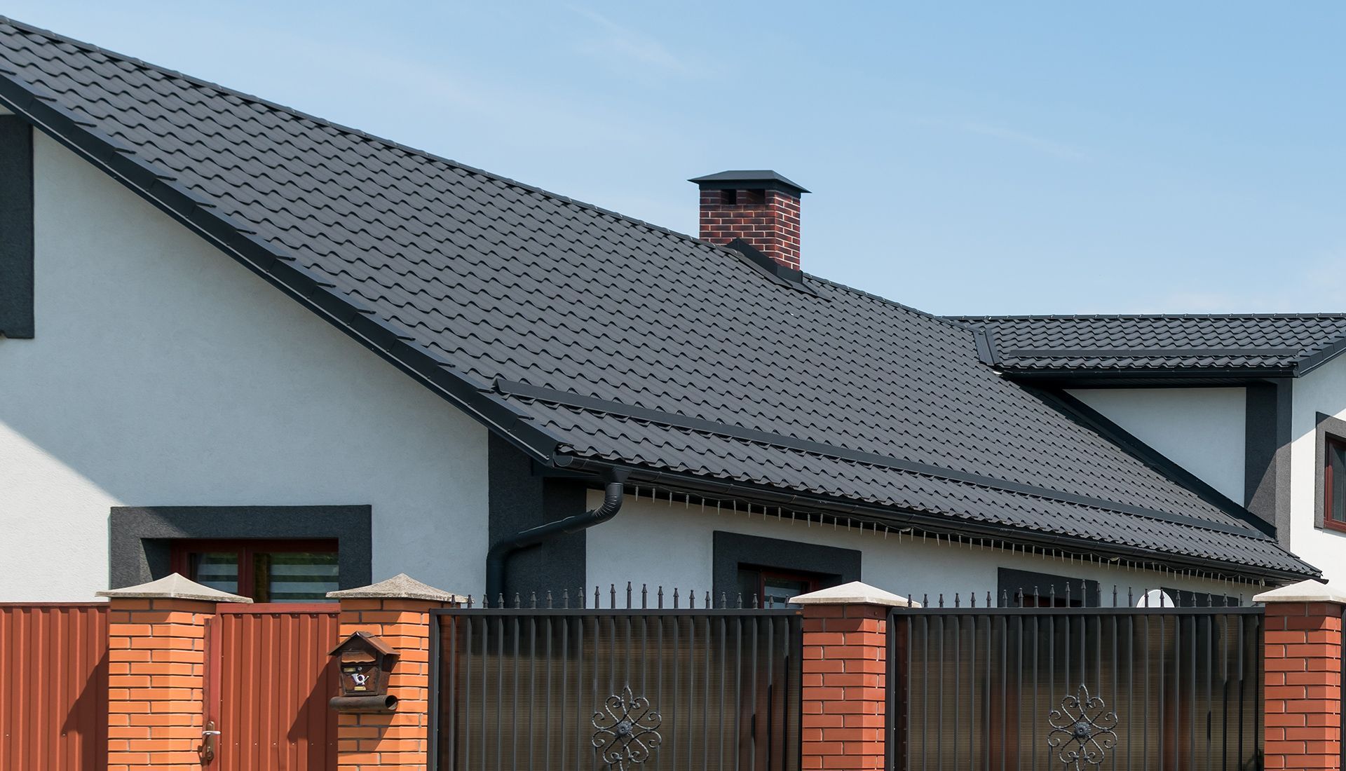 A white house with a black roof and a black fence