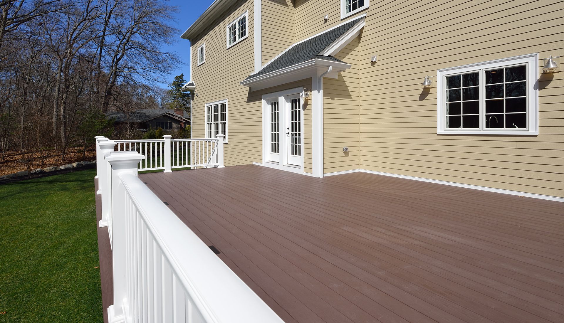 A large deck with a white railing in front of a house